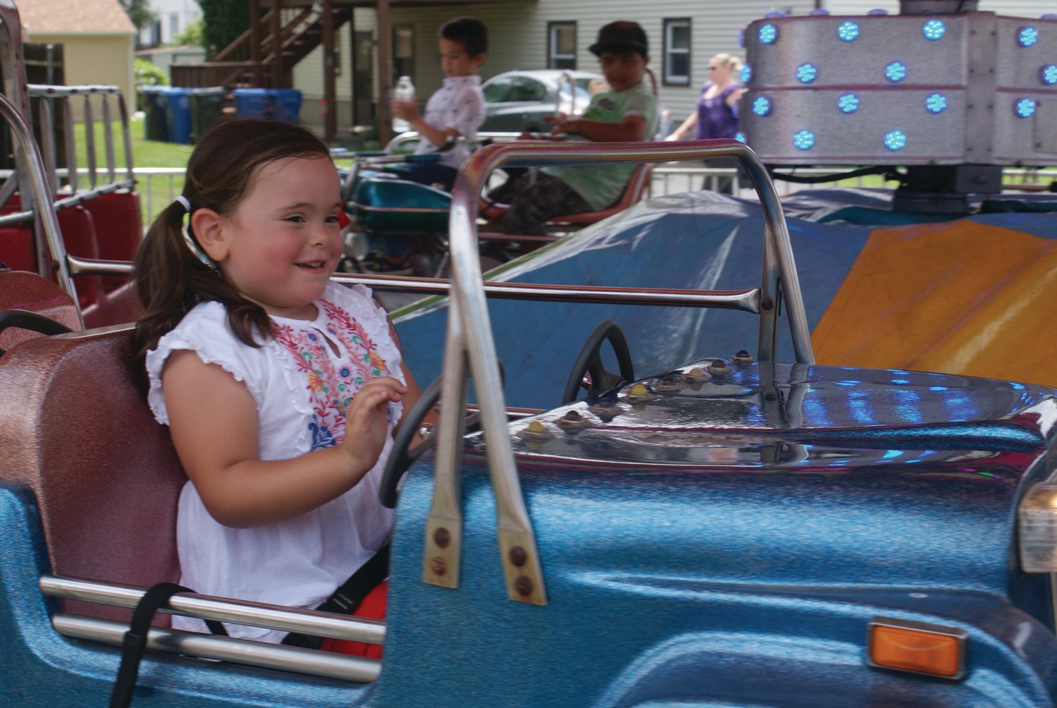 RIDING ALONG:  Lily Tanner, 5, enjoys her car ride at the amusement section at St. Mary’s Feast on Sunday. 